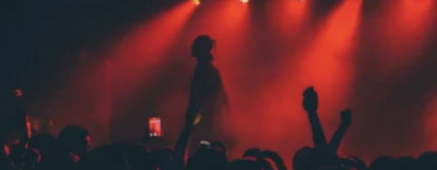 Performer on stage under red concert lighting