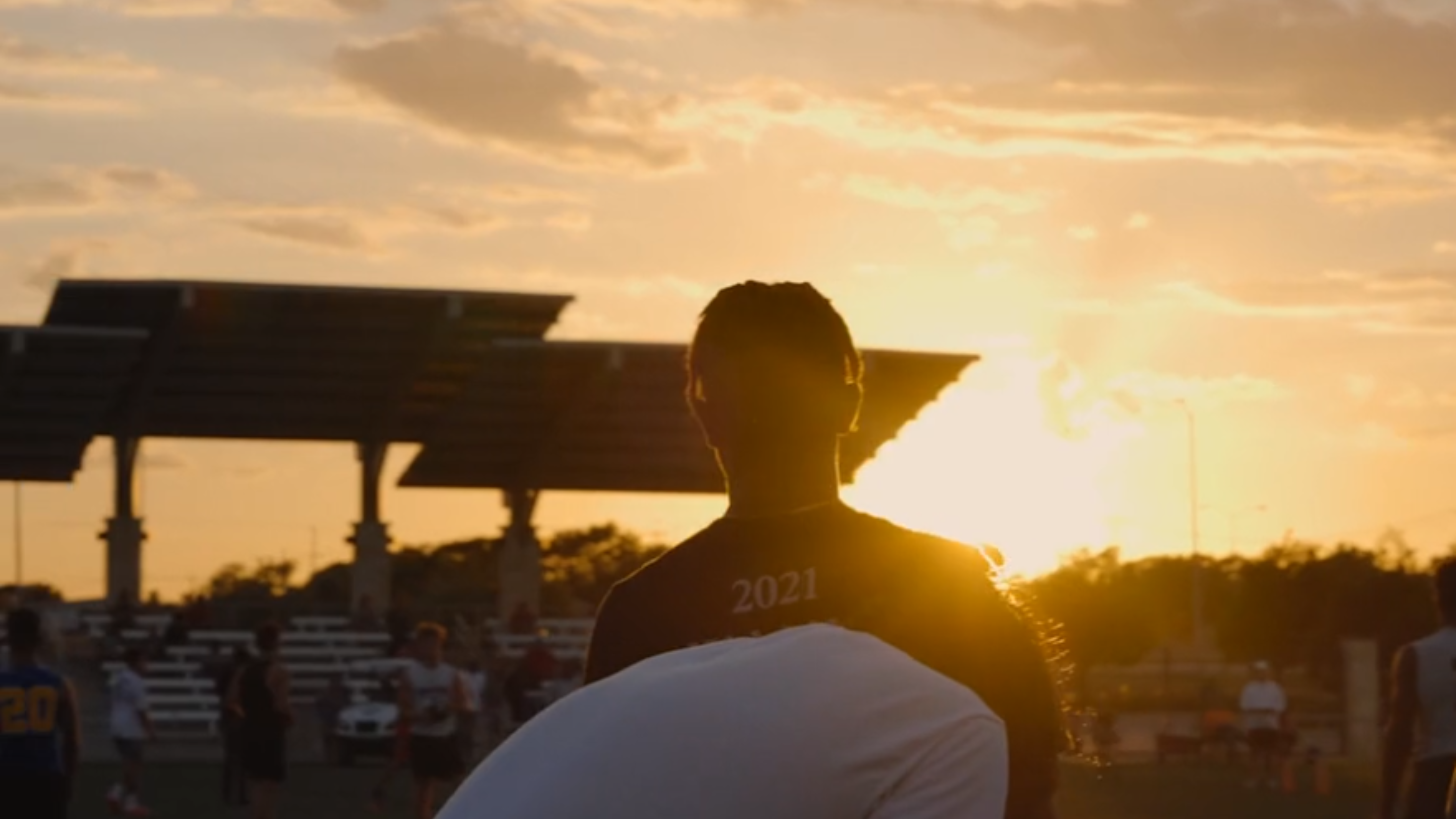 A person is standing in a field as the sun sets.